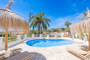 A swimming pool with lounge chairs and thatched umbrellas, surrounded by palm trees and a white fence. - CostaBlancaDreams - Casa Juleo in Benissa (Benissa)