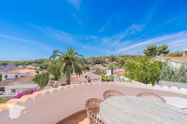 Una terraza con mesa y sillas, con vistas a una zona residencial con casas y árboles.