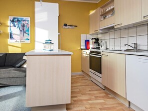 A compact kitchen with a central island, a built-in oven, and a microwave.