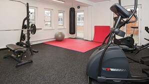 Un gimnasio con equipo de ejercicio, un saco de boxeo y una colchoneta roja.