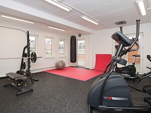 Ett gym med träningsredskap, en boxningssäck och en röd matta.