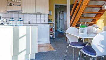 A modern kitchen with white cabinets, a central island, and a dining area with white chairs and a table.