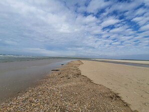 A beach with a pebbly shoreline and a clear sky.
