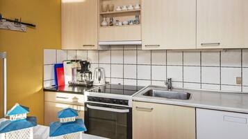 A kitchen with white cabinets, a black stove, a sink, and a coffee maker.