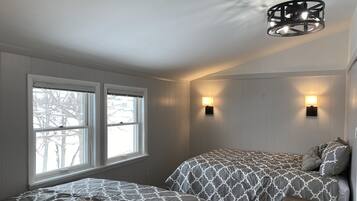 Un dormitorio con dos camas, una ventana e iluminación en la pared.