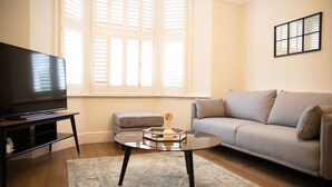 A living room with a television, a sofa, a coffee table, and a window with blinds. - York Minster-3 bed-Sleeps 6-Fireplace-Free Parking (York)