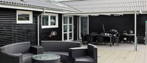 A covered patio with outdoor furniture, a grill, and a satellite dish.
