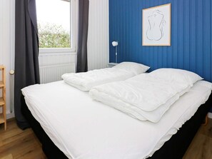 A bedroom with a bed, a window with curtains, a radiator, and a framed picture on the wall. - 4 Star Holiday Home in Hadsund (Hadsund)