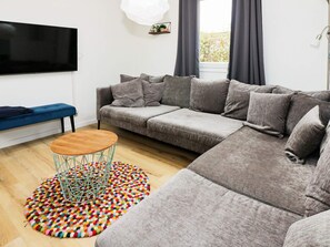 A modern living room with a sectional sofa, a round coffee table, and a colorful rug. - 4 Star Holiday Home in Hadsund (Hadsund)