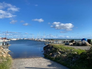 A marina with boats docked, a clear sky, and a calm waterway.