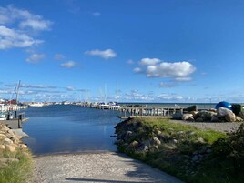 Un puerto deportivo con barcos amarrados, cielo despejado y agua tranquila.