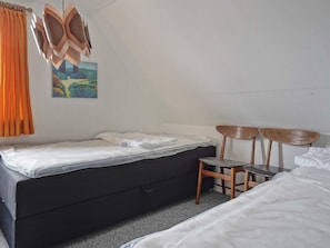 Ein Zimmer mit einem Bett, einem Sessel, einem Schreibtisch und einem Bild an der Wand.
