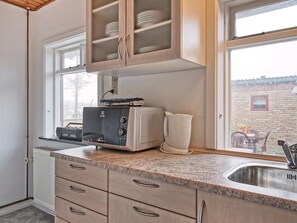 A kitchen with a built-in microwave, a kettle, and a window with a view of the outside. - 8 Person Holiday Home in Hasle (Hasle)
