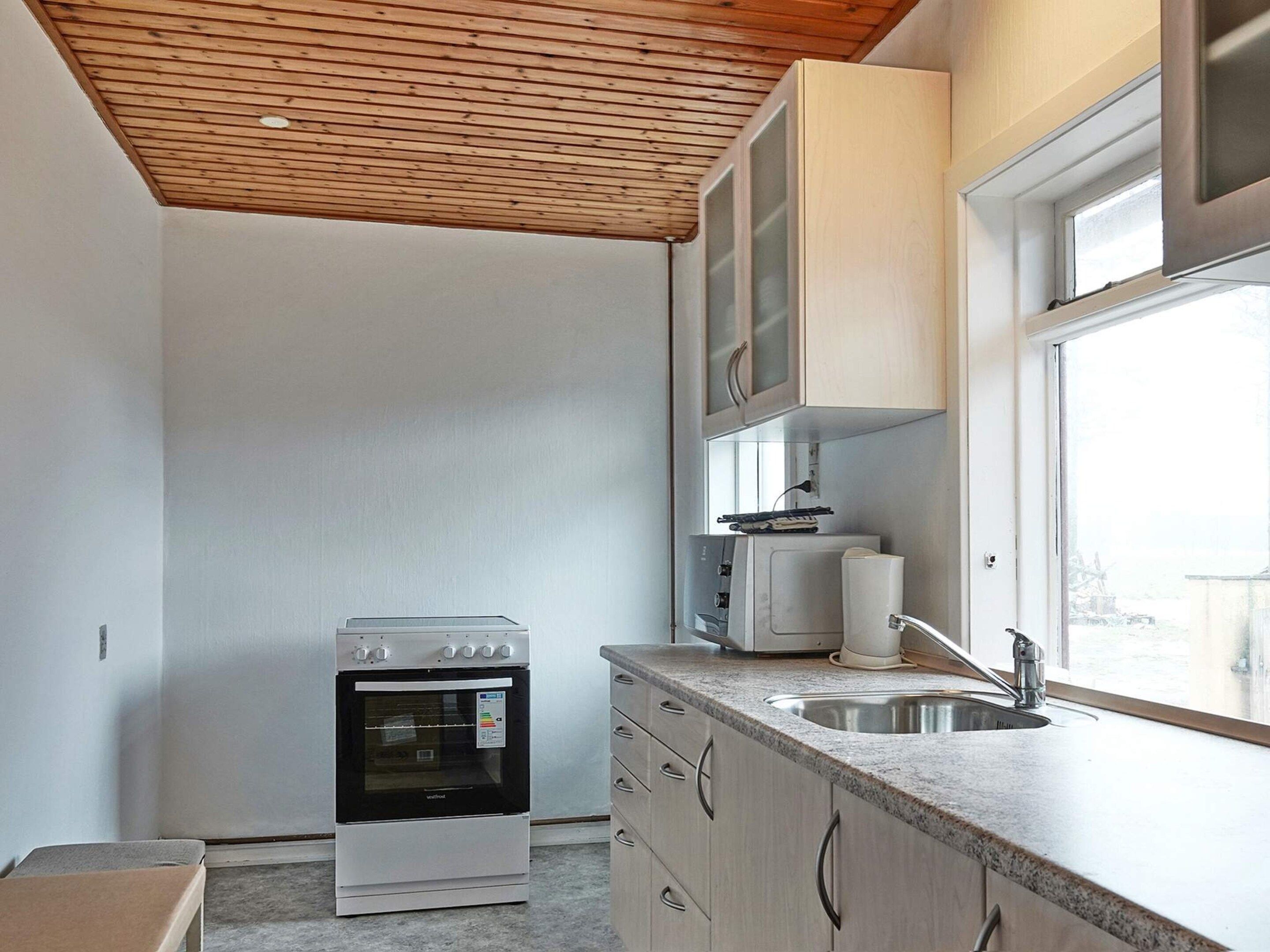 A compact kitchen with a built-in oven, a sink, and upper cabinets.