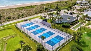 Ein Resort mit mehreren Schwimmbecken, einem Strand und Palmen.
