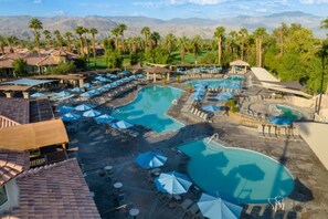 Een resort met meerdere zwembaden, terrasjes en palmbomen.