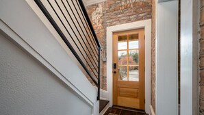 A staircase with a black railing leading to a wooden door with a glass panel.