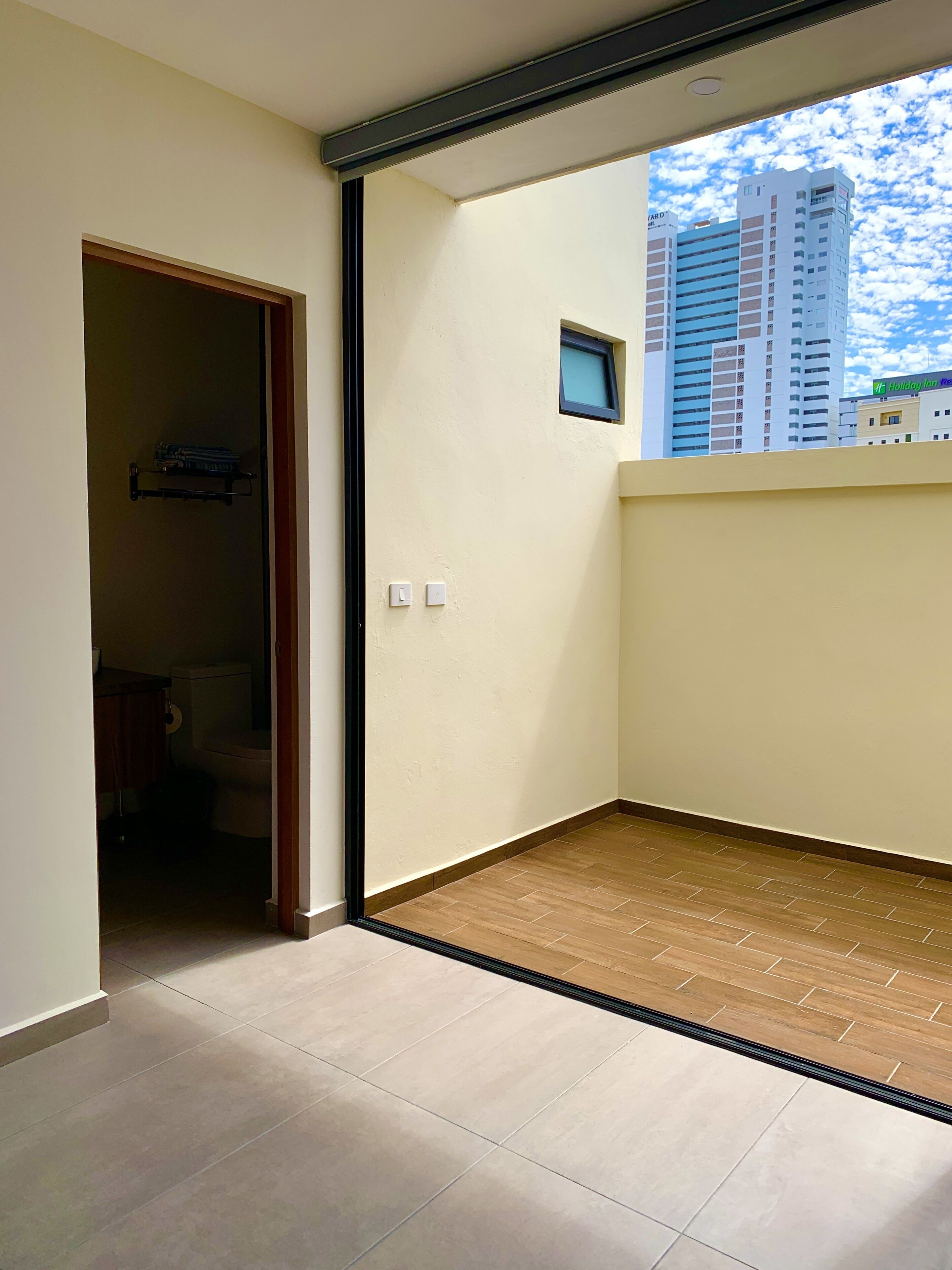 Une pièce avec vue sur la ville, une petite fenêtre et une porte donnant sur une salle de bain.