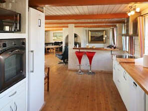 A kitchen with a built-in oven, a dining area with a table and chairs, and a bar area with stools. - 4 Star Holiday Home in Hadsund (Hadsund)