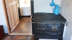 A kitchen with a black stove, a blue kettle, and a wooden door. - 4 Star Holiday Home in Hadsund (Hadsund)