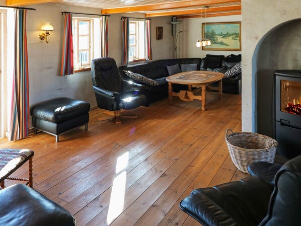 A cozy living room with a fireplace, leather furniture, and a wooden floor.