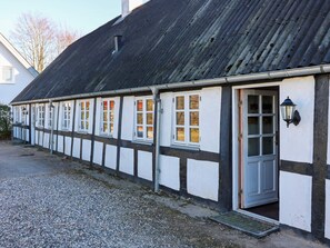 Un bâtiment doté d’un toit noir et de murs blancs, avec de nombreuses fenêtres et une porte.