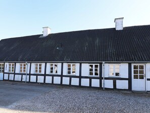 A long, single-story building with a corrugated metal roof and white-framed windows. - 4 Star Holiday Home in Hadsund (Hadsund)