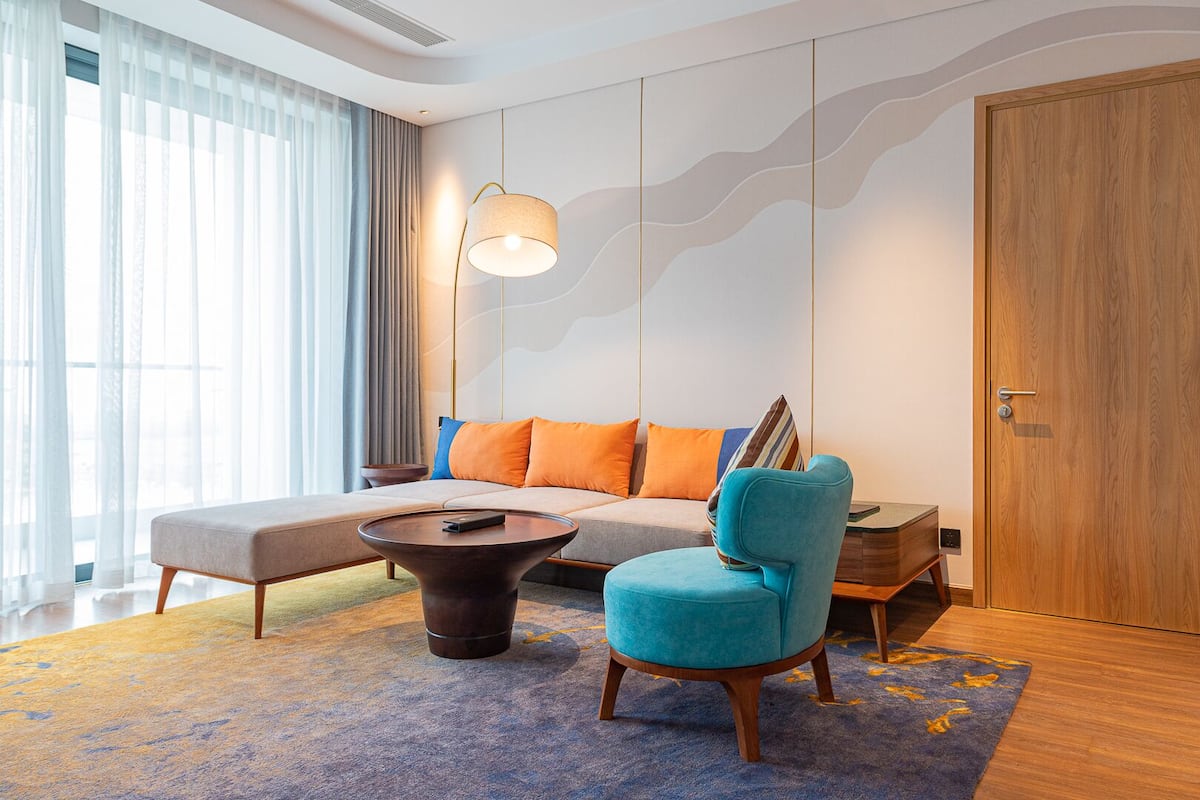 A modern living room with a sofa, a coffee table, a blue armchair, and a wooden side table.
