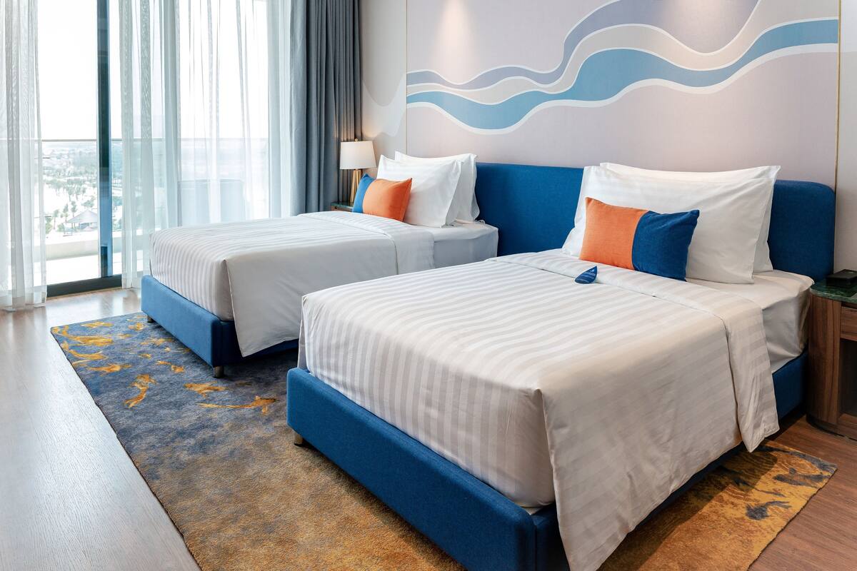 A hotel room with two beds, a view of the city, and a modern design.