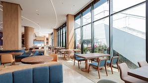 A modern indoor space with seating areas, tables, and large windows offering views of the outdoors. - Dream Dragon Resort (Hai Phong)