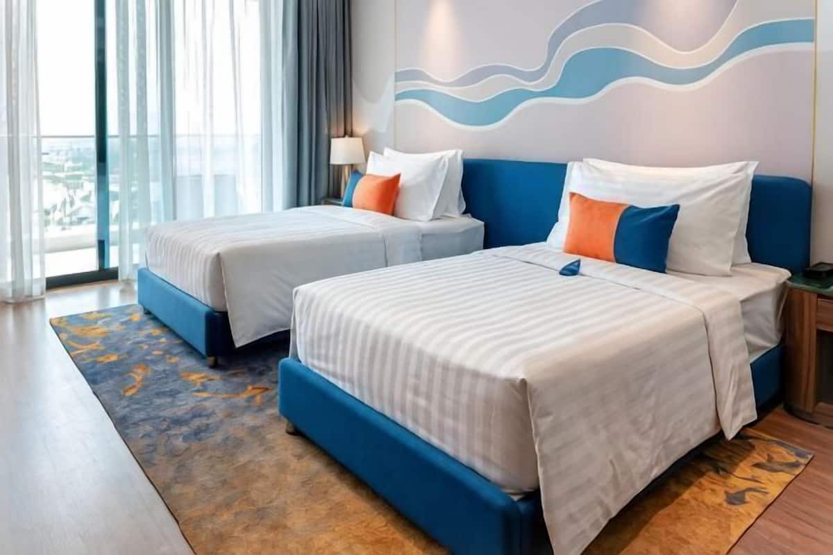 A hotel room with two beds, a view of the city, and a modern design.