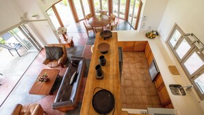 A spacious living area with a wooden dining table, leather sofa, and a kitchen with a large island. - Malaqereqere Villas Ocean/Pool View, Villa 3 (Sigatoka)