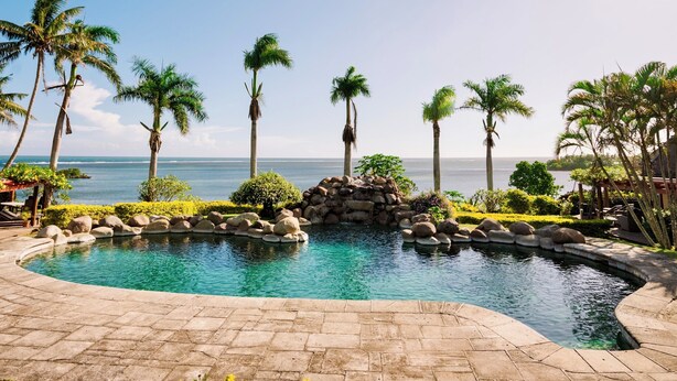 A pool with a view of the ocean, surrounded by palm trees and a stone wall. - Malaqereqere Villas Ocean/Pool View, Villa 3 (Sigatoka)
