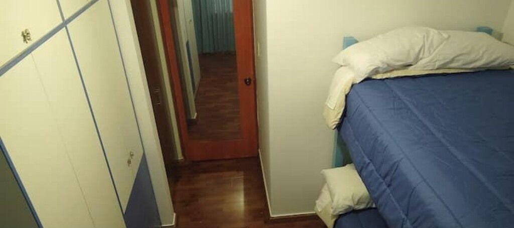 Un corridoio stretto che porta a una camera da letto con un letto, un armadio e una porta.