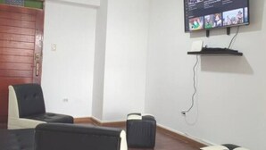 Une pièce avec un téléviseur fixé au mur, une petite étagère en dessous et une porte avec un panneau en bois.