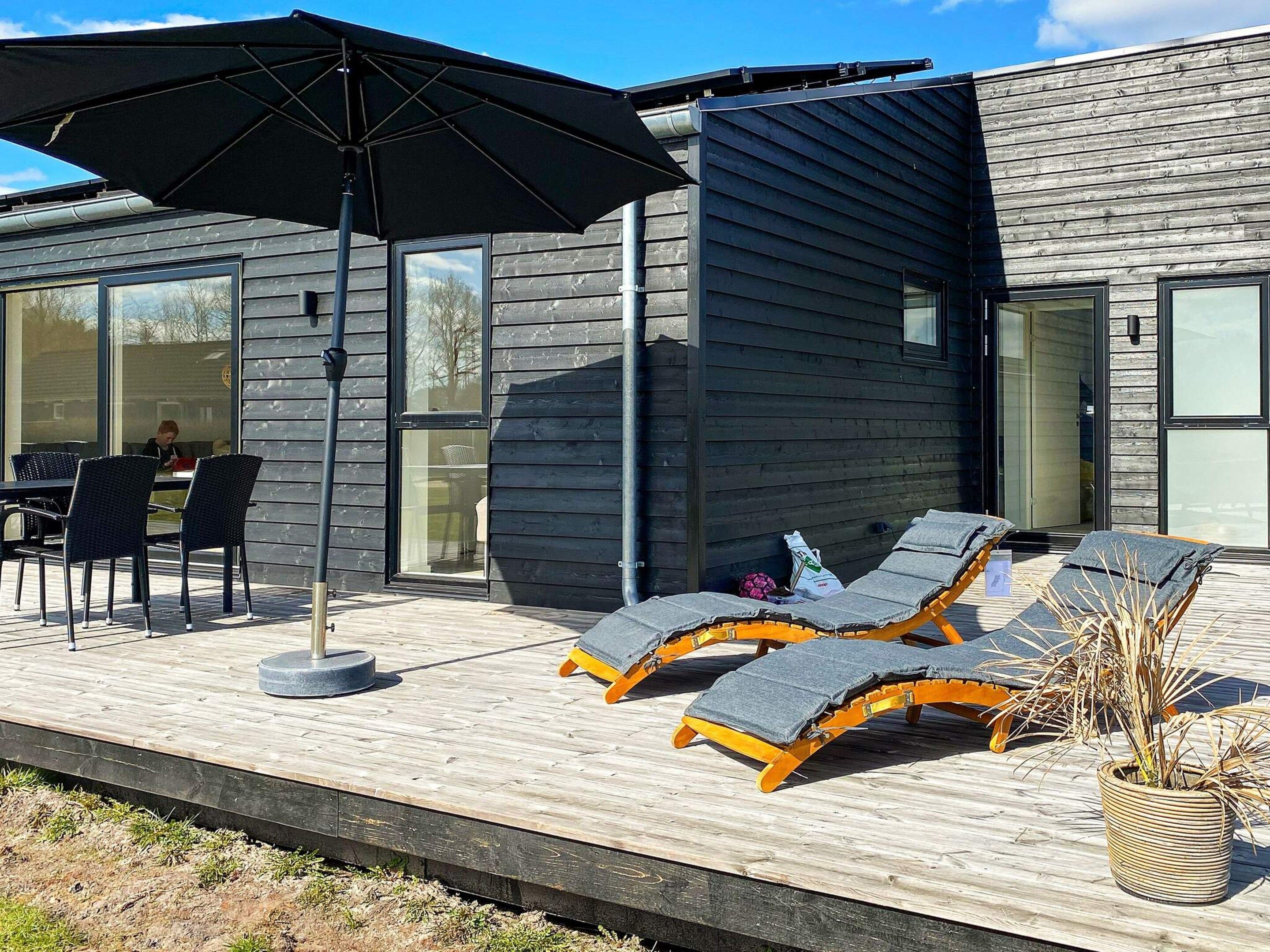 A modern outdoor seating area with lounge chairs and a large umbrella.