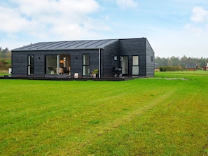 Et moderne hus med fladt tag, store vinduer og en græsplæde.