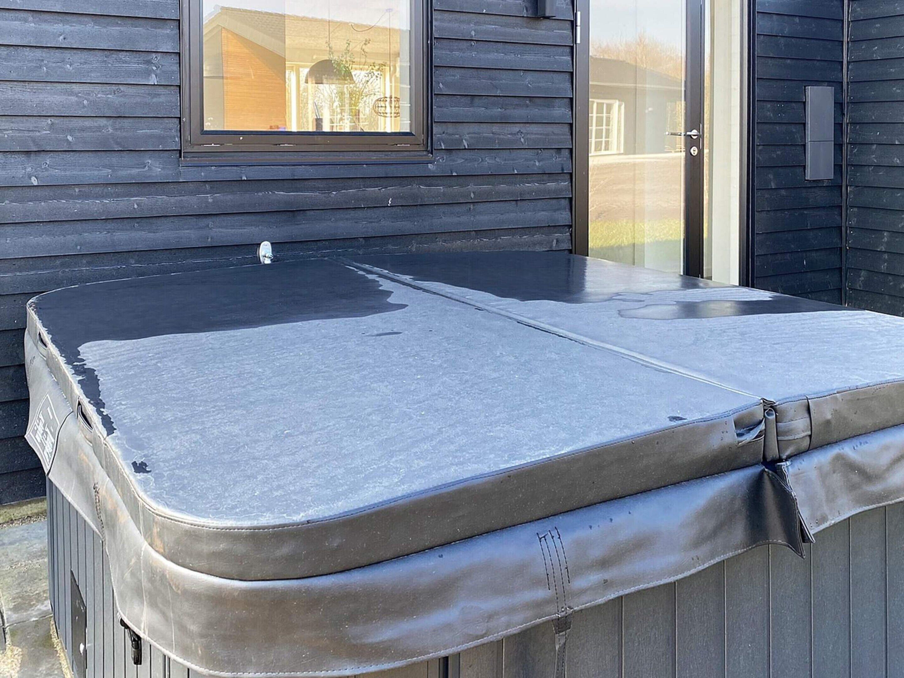 Un jacuzzi con tapa, ubicado frente a una pared de madera con ventana.