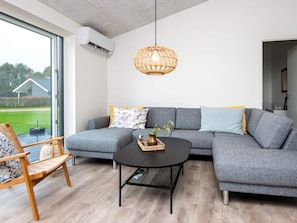A modern living room with a grey sectional sofa, a round black coffee table, and a wicker pendant light.