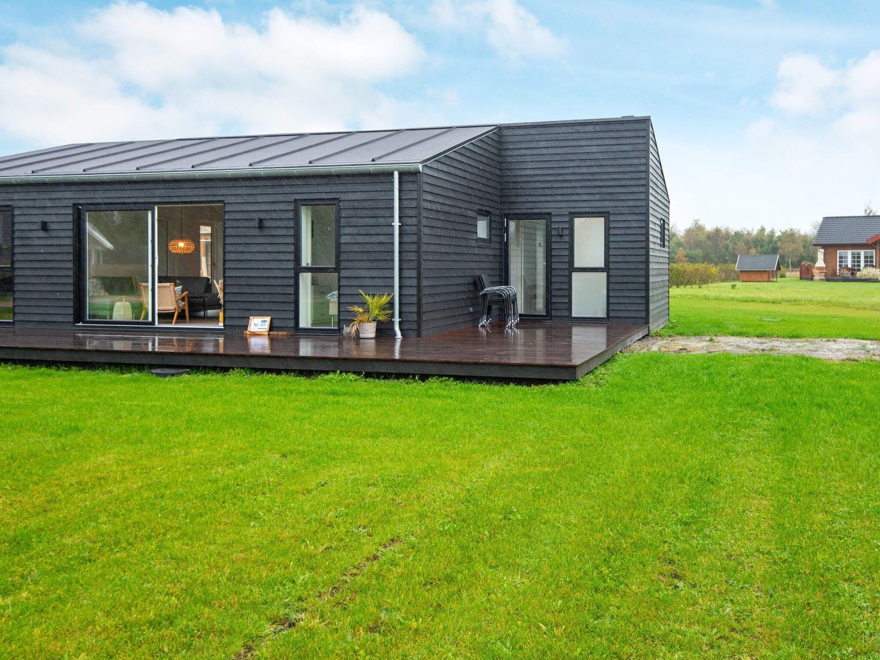 A modern house with a flat roof, large windows, and a covered deck.
