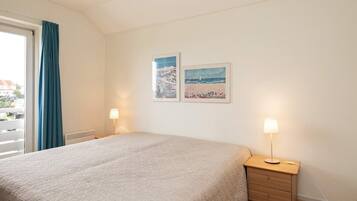 A hotel room with a bed, a nightstand, two wall-mounted lamps, and two framed pictures.