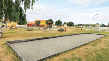 An outdoor recreational area with a concrete court, picnic tables, and playground equipment.