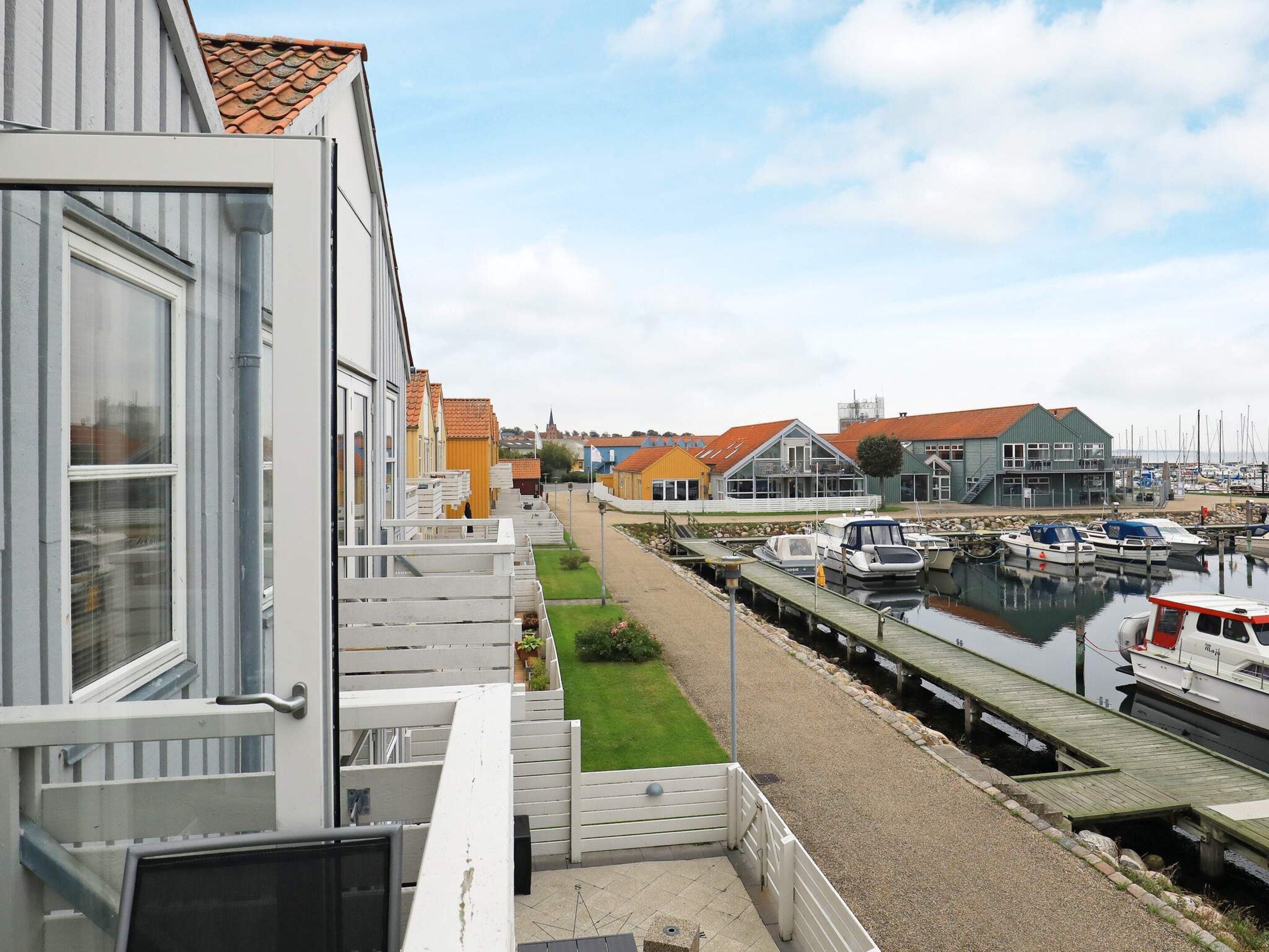 A marina with boats docked, a grassy area, and buildings with red roofs.