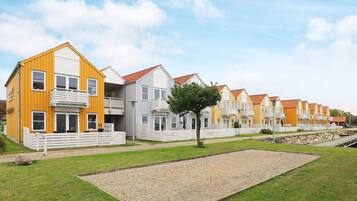 A row of modern, multi-story residential buildings with balconies, set in a grassy area with a gravel path.
