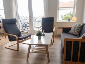 A modern living room with a sofa, two chairs, a table, and a view of the outside.