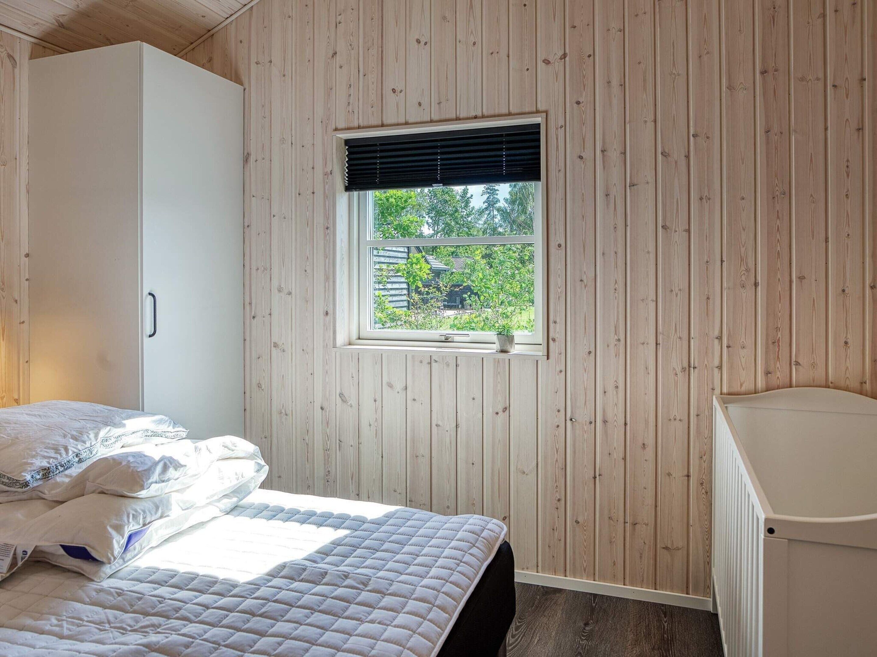 A bedroom with a bed, a window with blinds, a radiator, and a wardrobe.