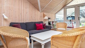 A cozy room with a grey sofa, wicker chairs, a white table, and a wooden ceiling. - 10 Person Holiday Home in Stege (Stege)