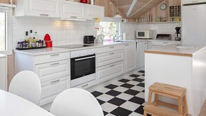 A modern kitchen with white cabinetry, a black and white checkered floor, and a wooden ceiling. - 10 Person Holiday Home in Stege (Stege)