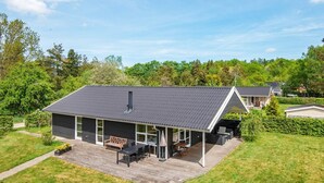 A modern house with a large deck, a covered outdoor seating area, and a well-maintained garden. - 4 Star Holiday Home in Silkeborg (Silkeborg)