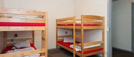 A dormitory room with bunk beds and a door.